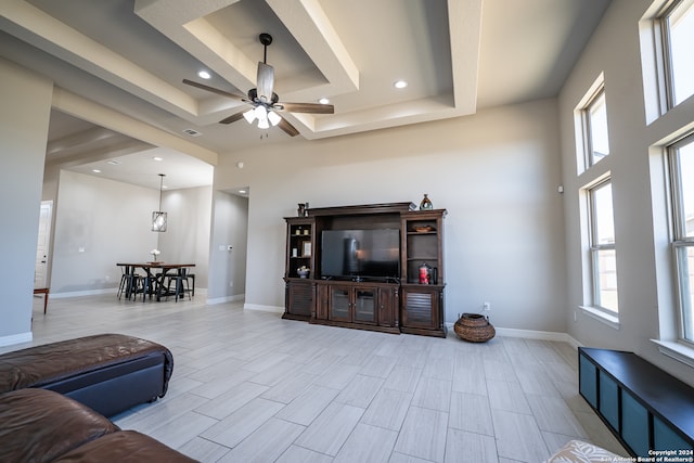 living room featuring ceiling fan, a raised ceiling, and a healthy amount of sunlight