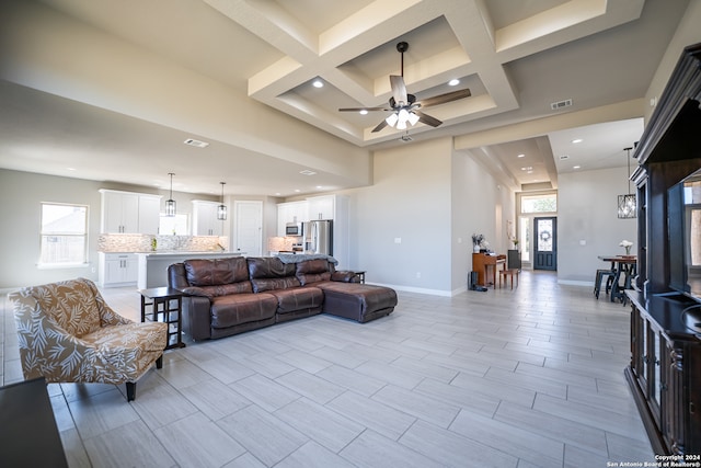 living room with beamed ceiling, coffered ceiling, and ceiling fan