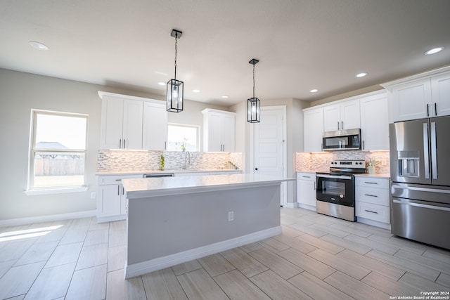 kitchen featuring pendant lighting, appliances with stainless steel finishes, backsplash, a center island, and white cabinets