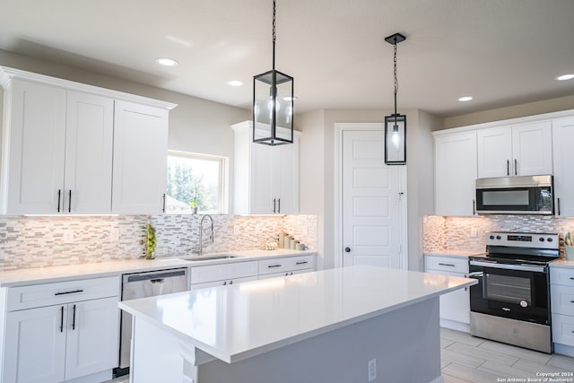 kitchen featuring pendant lighting, appliances with stainless steel finishes, white cabinetry, backsplash, and a center island