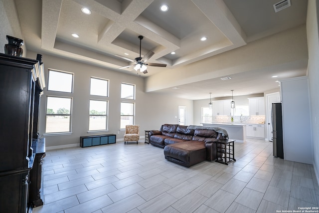 living room featuring coffered ceiling, ceiling fan, light tile patterned flooring, a tray ceiling, and beam ceiling