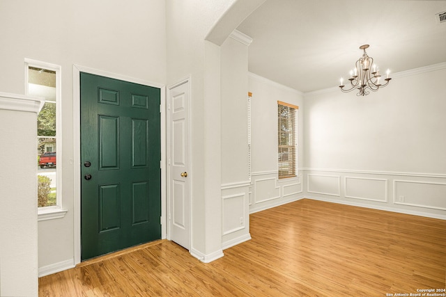 entryway with a chandelier, light hardwood / wood-style flooring, and ornamental molding