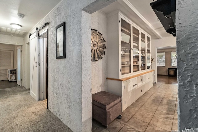 corridor featuring tile patterned floors and a barn door