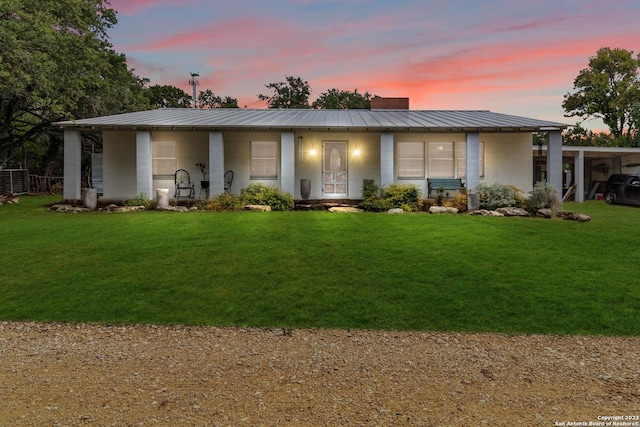 view of front of house with metal roof, concrete block siding, a standing seam roof, and a front lawn