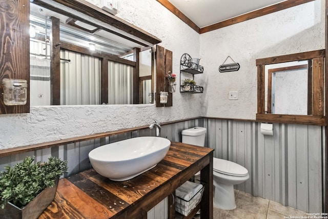 half bathroom featuring vanity, a wainscoted wall, toilet, wood walls, and a textured wall