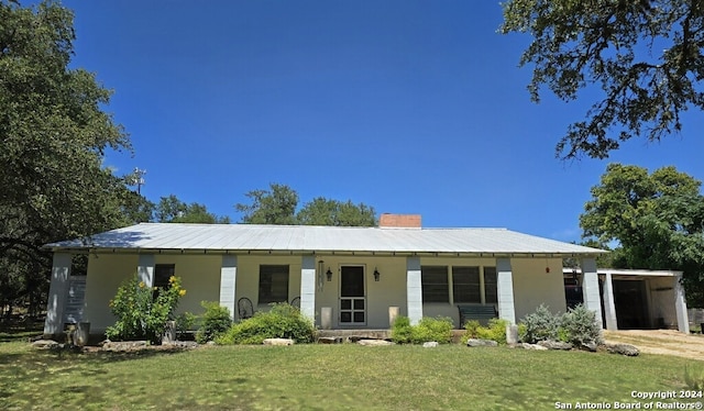 view of front of home featuring a chimney, metal roof, and a front lawn