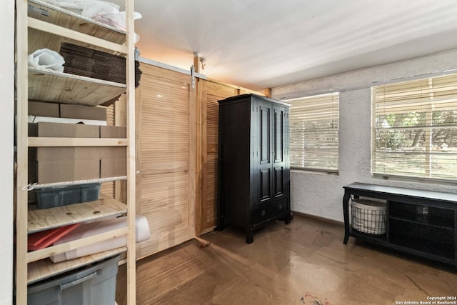 bedroom with a textured wall, concrete floors, and baseboards