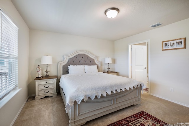 bedroom with baseboards, visible vents, and light colored carpet