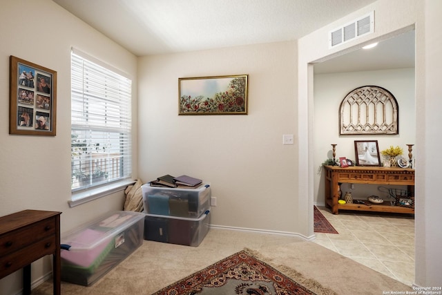 interior space with light tile patterned floors, baseboards, visible vents, and light colored carpet