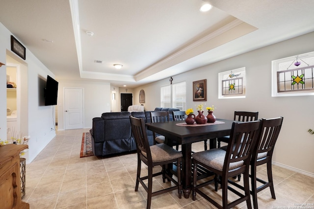 dining area with light tile patterned floors, baseboards, and a raised ceiling