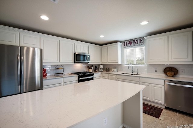 kitchen featuring tasteful backsplash, white cabinetry, stainless steel appliances, and a sink