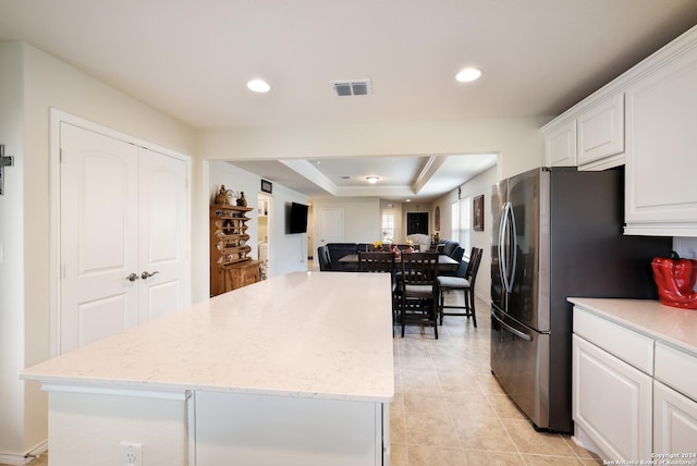 kitchen with a tray ceiling, visible vents, freestanding refrigerator, open floor plan, and white cabinets