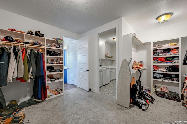 walk in closet with washing machine and dryer and light carpet