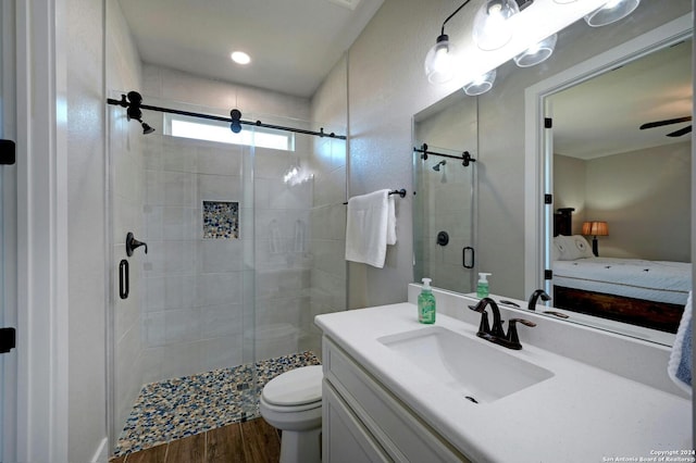 bathroom with ceiling fan, toilet, vanity, walk in shower, and hardwood / wood-style flooring