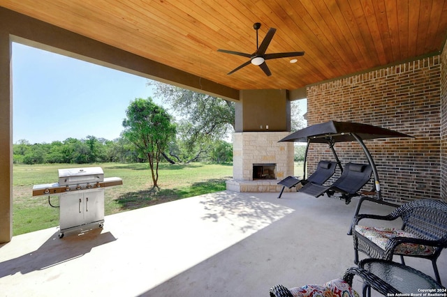 view of patio with ceiling fan, grilling area, and an outdoor stone fireplace