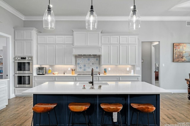 kitchen with light wood-type flooring, a kitchen bar, and stainless steel double oven