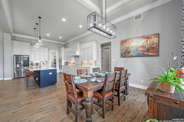 dining room featuring sink, ornamental molding, and hardwood / wood-style flooring