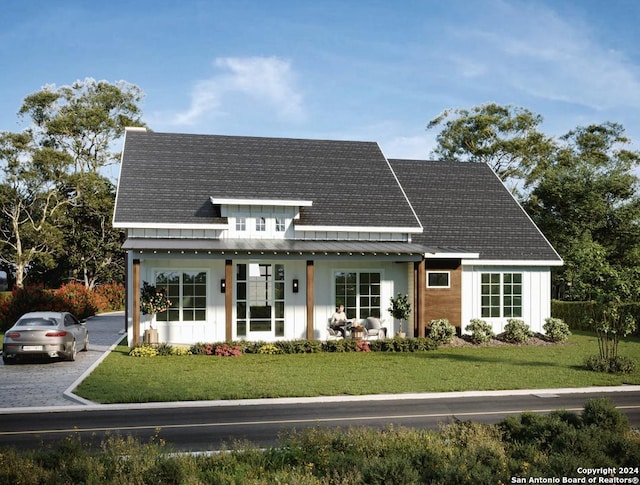 view of front of house with a shingled roof, covered porch, a standing seam roof, metal roof, and a front lawn