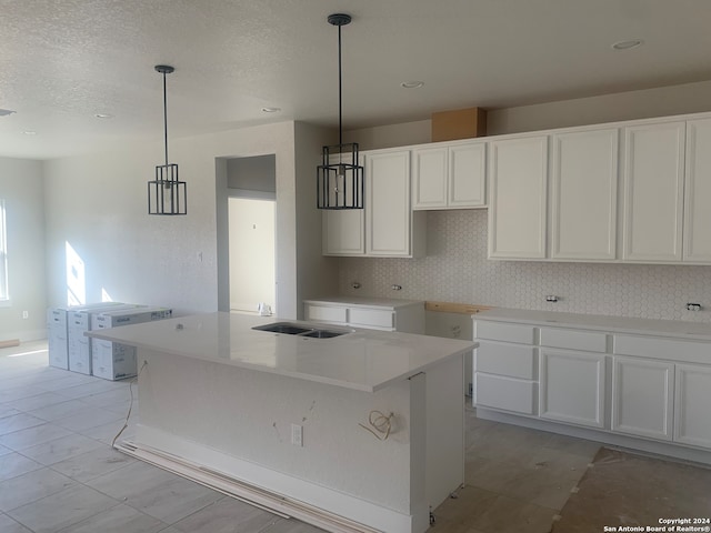 kitchen featuring light tile patterned floors, white cabinets, a center island, and decorative light fixtures