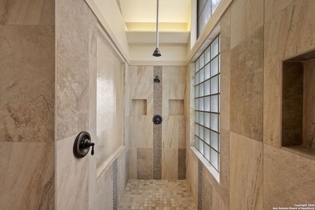 bathroom featuring a tray ceiling, tile walls, and a tile shower