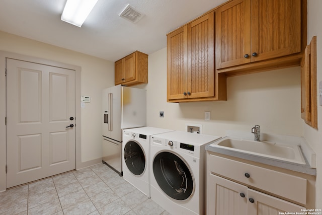 laundry room with sink, washing machine and dryer, light tile patterned flooring, and cabinets