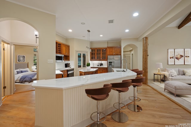 kitchen with appliances with stainless steel finishes, sink, hanging light fixtures, and light hardwood / wood-style flooring