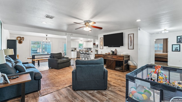 living room with a textured ceiling, ceiling fan with notable chandelier, and hardwood / wood-style floors