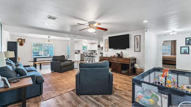 living area featuring recessed lighting, visible vents, a textured ceiling, wood finished floors, and ceiling fan with notable chandelier