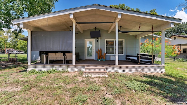 back of property featuring ceiling fan and a yard