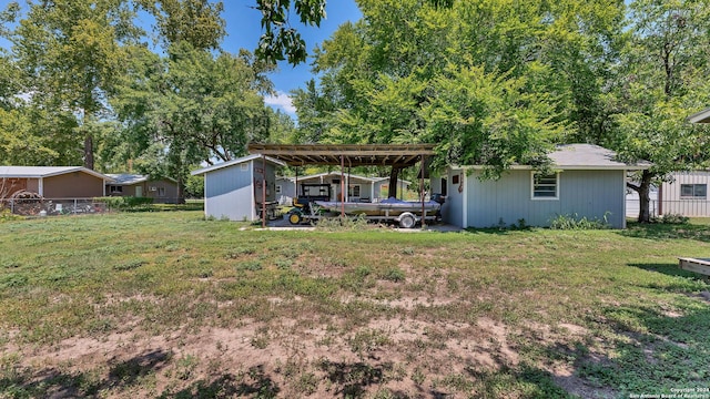 view of yard featuring fence, a carport, and an outbuilding