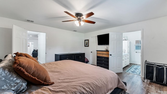 bedroom featuring dark wood-style floors, visible vents, ensuite bathroom, and a ceiling fan