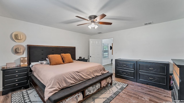 bedroom featuring a ceiling fan, visible vents, and wood finished floors