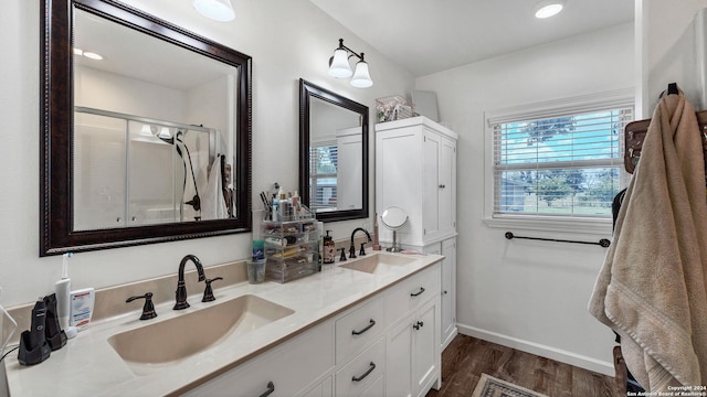 full bath featuring a shower stall, baseboards, a sink, and wood finished floors