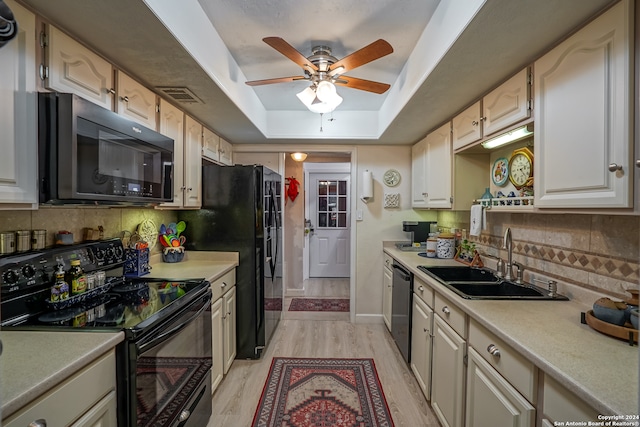 kitchen with ceiling fan, a raised ceiling, backsplash, sink, and black appliances