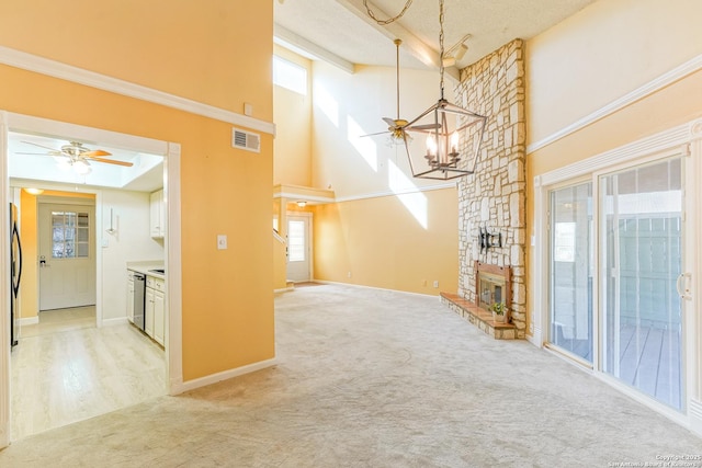 interior space with a fireplace, ceiling fan, a wealth of natural light, and light colored carpet