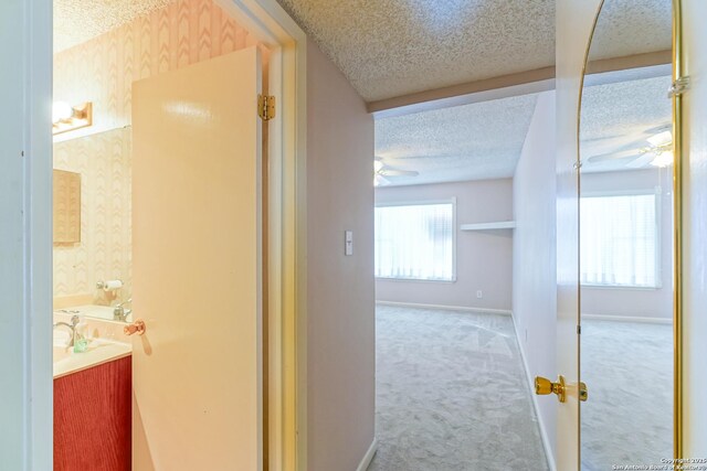 bedroom featuring a textured ceiling, ceiling fan, and light colored carpet