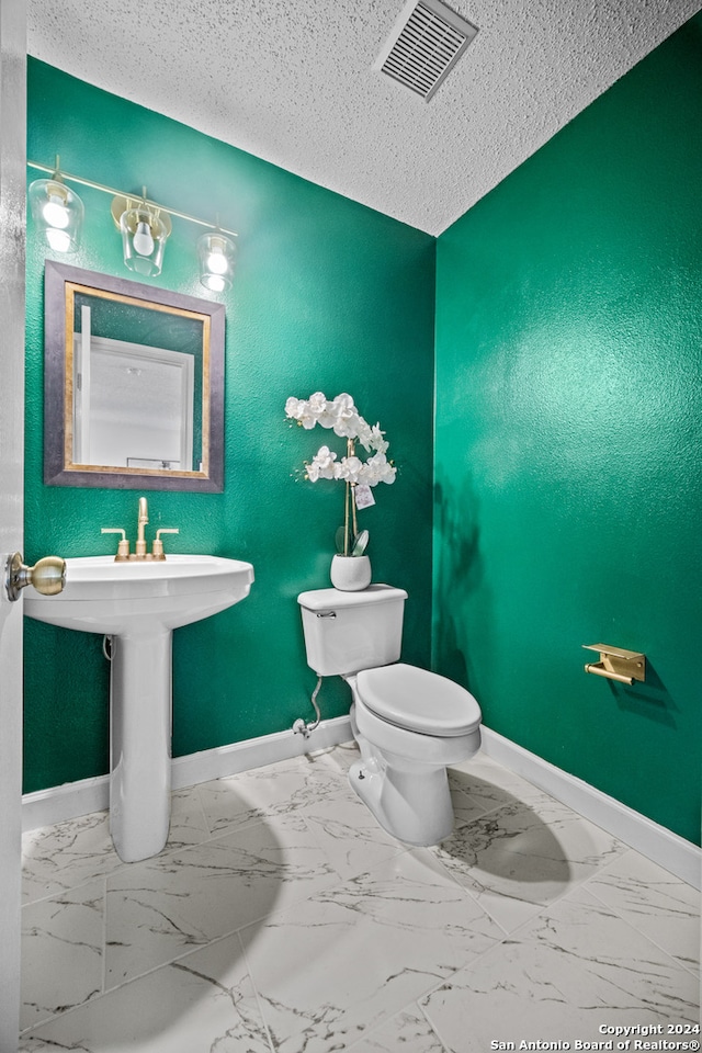 bathroom featuring tile patterned flooring, a textured ceiling, and toilet