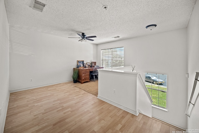 interior space featuring ceiling fan, light hardwood / wood-style floors, and a textured ceiling