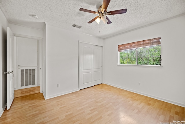 unfurnished bedroom with ceiling fan, a closet, a textured ceiling, and light hardwood / wood-style floors