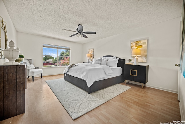 bedroom with light wood-type flooring, ceiling fan, and a textured ceiling