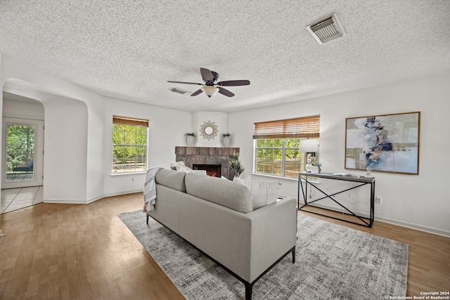 living room featuring a textured ceiling, ceiling fan, and light wood-type flooring