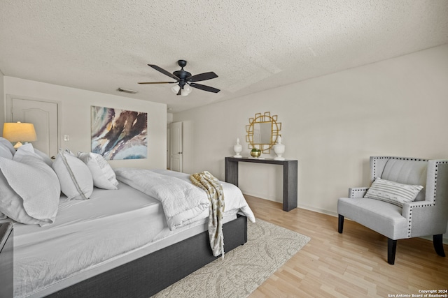 bedroom with ceiling fan, light wood-type flooring, and a textured ceiling