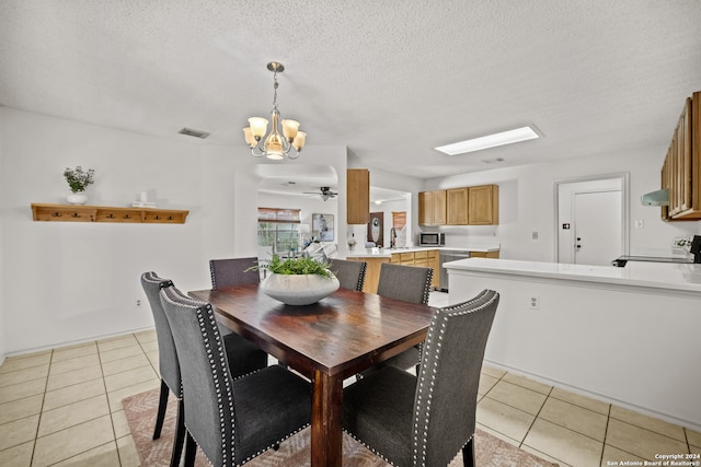 tiled dining space featuring a textured ceiling, ceiling fan with notable chandelier, and sink