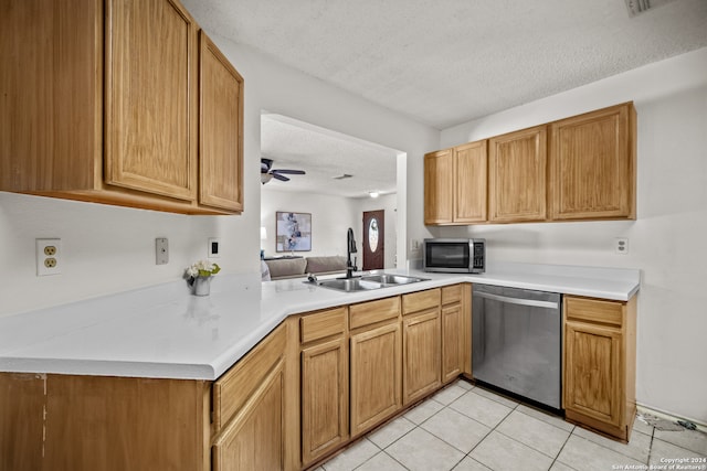 kitchen with ceiling fan, light tile patterned floors, sink, kitchen peninsula, and stainless steel appliances