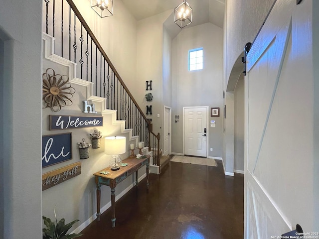 foyer with concrete floors, baseboards, stairs, and a high ceiling