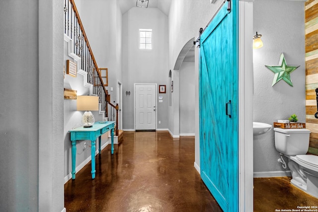 foyer with a barn door and high vaulted ceiling