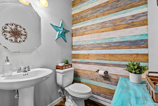 bathroom featuring wood walls and toilet