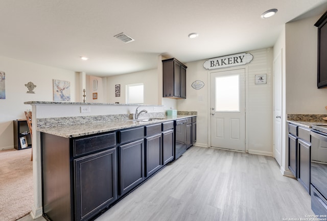 kitchen with dark brown cabinetry, sink, light stone counters, light wood-type flooring, and kitchen peninsula