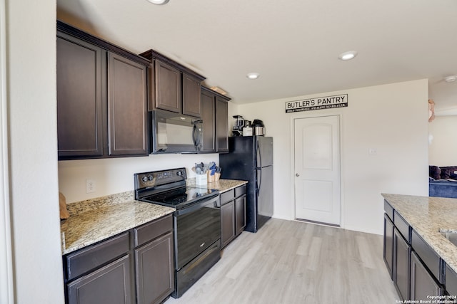 kitchen with light wood-type flooring, black appliances, dark brown cabinetry, and light stone countertops