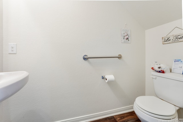 bathroom featuring wood-type flooring, vaulted ceiling, and toilet